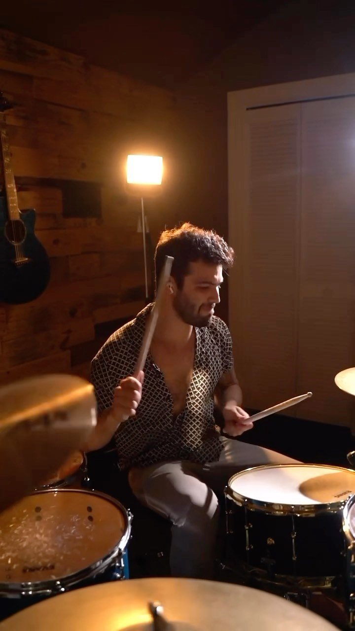 Blake McLain playing drums in warm studio light
